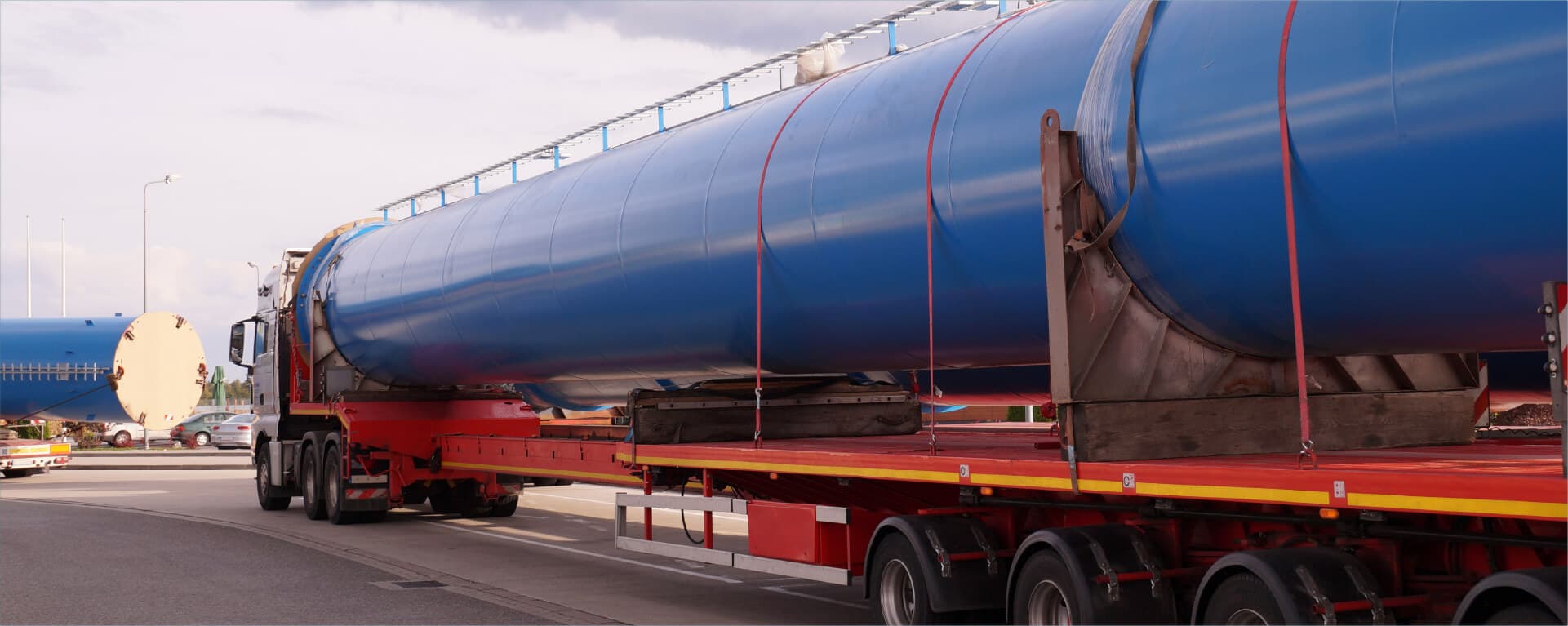 Extra-long industrial pipe section secured on a lowboy flatbed trailer